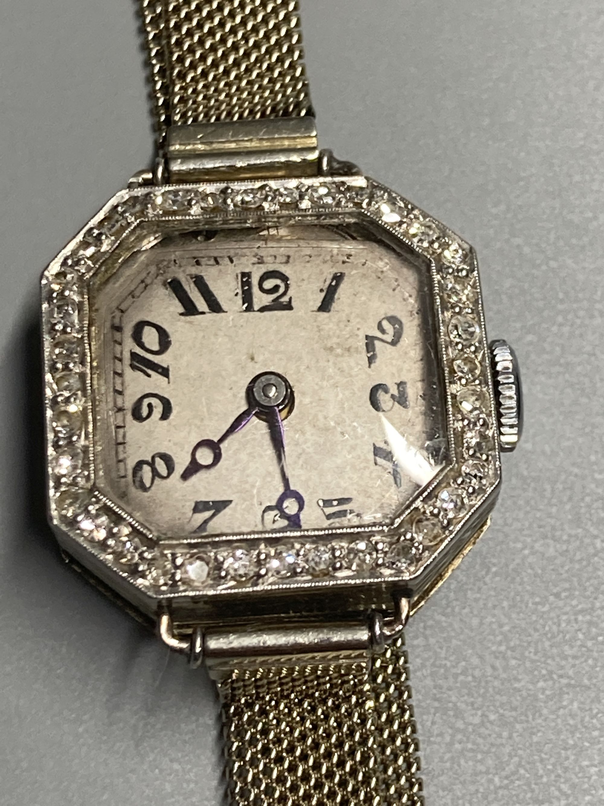 A ladys 1930s white metal and diamond bezel set manual wind wrist watch, on an 18ct mesh link bracelet,